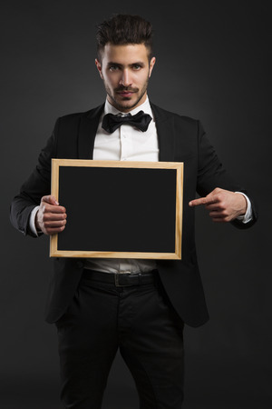Studio portrait of a handsome young man holding a chalkboardの写真素材