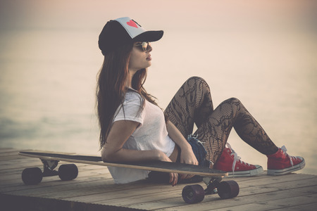 Beautiful fashion skater girl posing with  a skate boardの写真素材