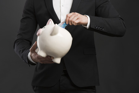 Portrait of a happy businessman holding a piggy bankの写真素材