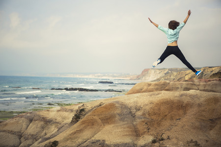 Young woman jump with a beautiful beach on the backgroundの写真素材
