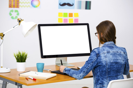Woman working at desk In a creative office using a computerの写真素材
