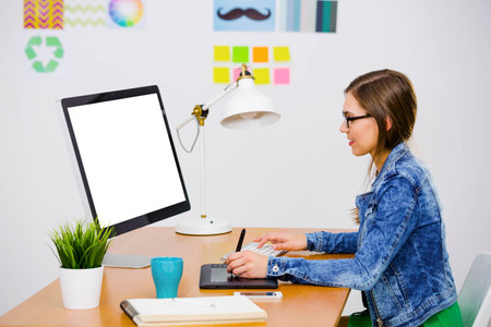 Woman working at desk In a creative office, using a computerの写真素材