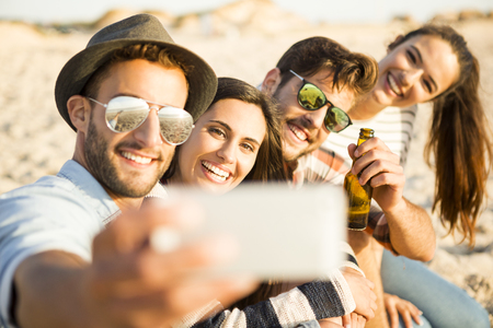 Group of friends at the beach making a selfie togetherの写真素材