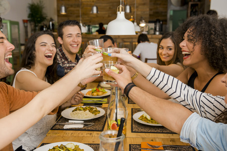 Group of friends toasting and looking happy at a restaurantの写真素材