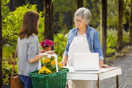 Mature women working in a flower shop and talking with a customerの写真素材