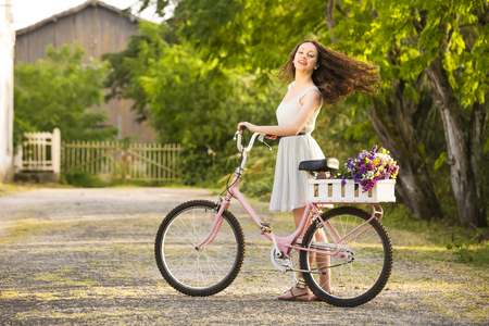 A beautiful young woman with her bicycle full of wildflowersの写真素材
