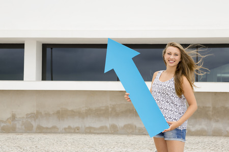 School concept - Teenage student holding a blue arrowsの写真素材