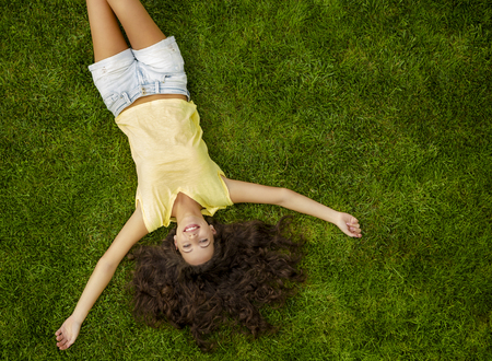 Outdoor portrait of a beautiful young woman lying on the grassの写真素材
