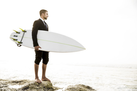 A Businessman holding is surfboard after a long day of work