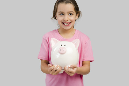 Cute little girl holding a piggybank with her savingsの写真素材