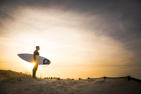 A surfer with his surfboard at the dunes looking to the wavesの写真素材