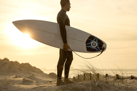 A surfer with his surfboard at the dunes looking to the wavesのeditorial素材