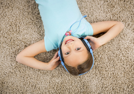 Little blonde girl at home listen music with headphonesの写真素材