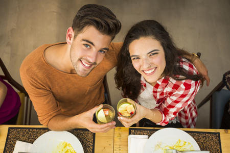 Young couple toasting and looking happy at a restaurantの写真素材