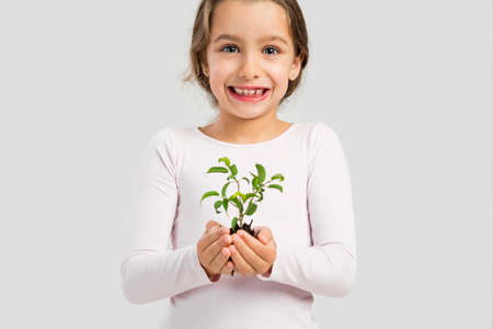 Cute little girl holding a green plant oh her handsの写真素材
