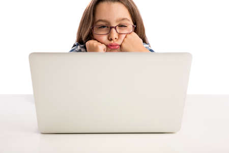 Little girl sitting on a desk and working with a laptop