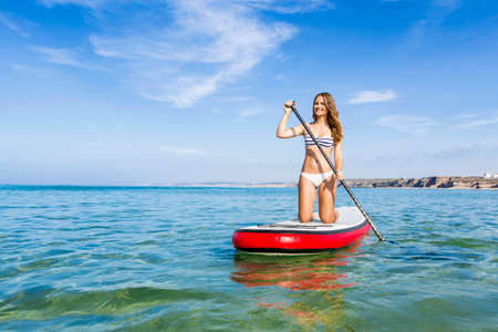 A beautiful woman practicing paddle on a beautiful sunny dayの写真素材