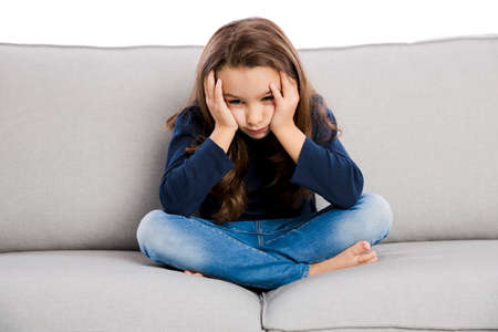 Little girl sitting on a couch and upset with somethingの写真素材