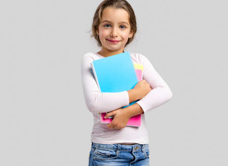 Smiling little student girl holding notebooksの写真素材