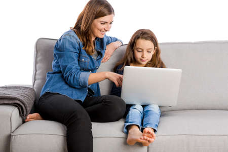 Mother teaching her little daughter working with a laptop