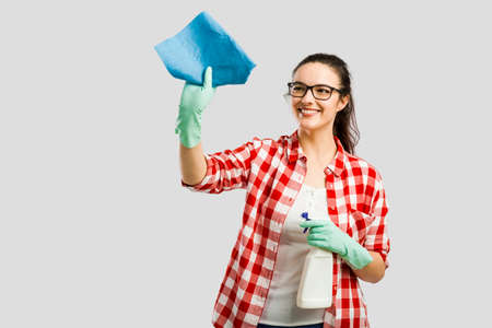 Pretty woman wearing gloves, using a cleaning spray and cleaning the house