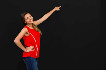 Beautiful woman standing in front of a dark board and pointing