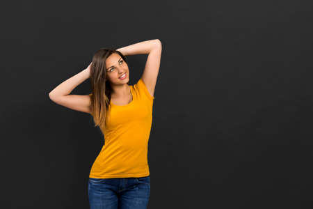 Beautiful woman in front of a black wall with a thoughtful expressionの写真素材