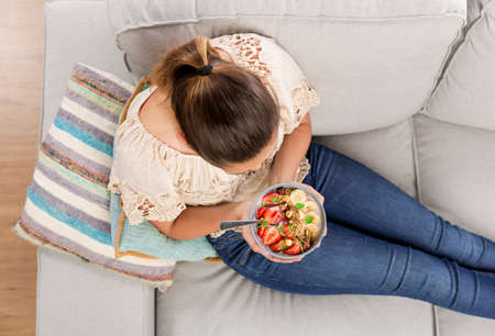 Top viw of a beautiful woman at home eating a healthy bowlの写真素材