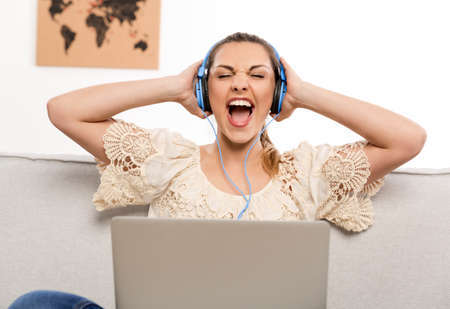 Beautiful woman at home working on her laptop and listening music