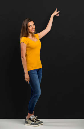 Beautiful woman standing in front of a dark board and pointingの写真素材