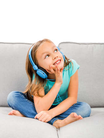 Little blonde girl at home listen music with headphonesの写真素材