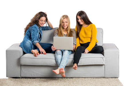 Happy teen girls at home with a laptopの写真素材