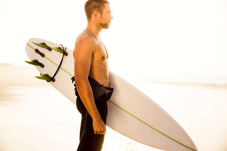 A surfer with his surfboard at the beach