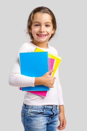 Smiling little student girl holding notebooksの写真素材