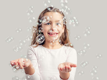 Cute little girl playing with soap bubbles