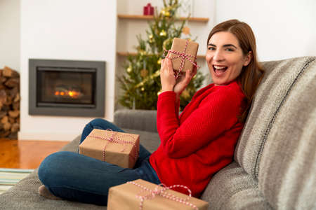 Beautiful happy woman at home holding Christmas presentsの写真素材