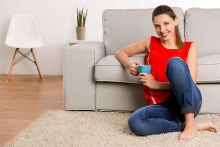 Beautiful happy woman at home drinking coffeeの写真素材