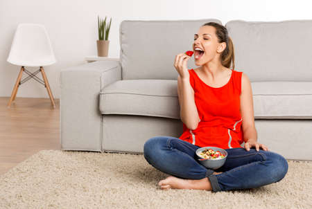 Beautiful happy woman at home eating a strawberries