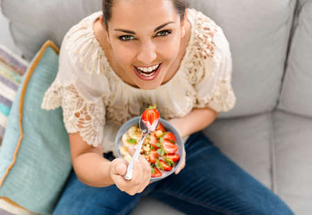 Beautiful happy woman at home eating a healthy bowlの写真素材