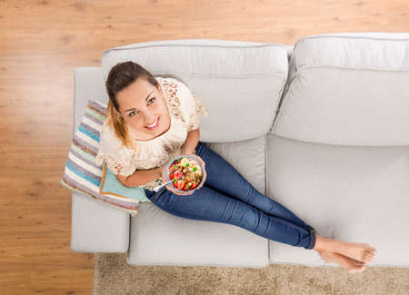 Top viw of a beautiful woman at home eating a healthy bowlの写真素材