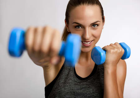 Young fitness woman making exercises with dumbbellsの写真素材