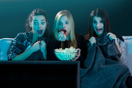 Teenage girls watching horror movie with popcornの写真素材