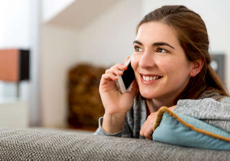 Happy beautiful woman at home sending text messages