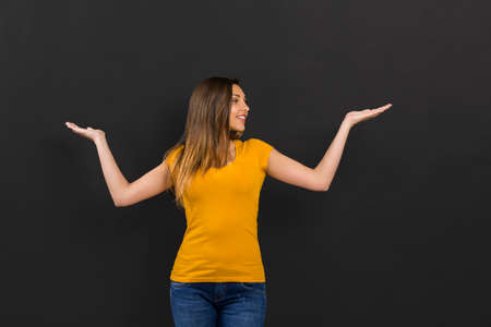 Beautiful woman with arms open in front of a black wall