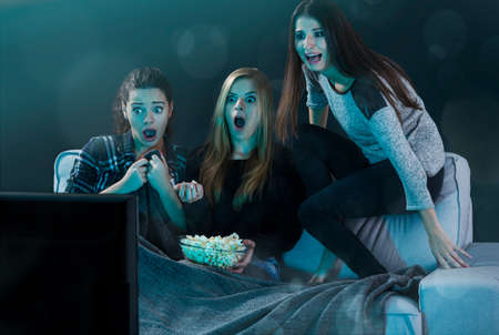 Teenage girls watching horror movie with popcornの写真素材