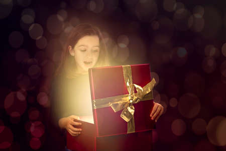 Little girl opening a magic box with light coming outの写真素材