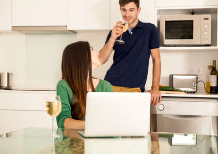 Young couple tasting wine and the women working on a laptopの写真素材