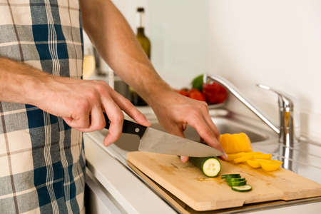 Young man on the kitchen cuting vegetables to cook