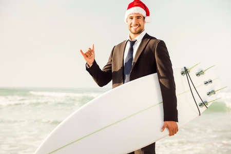 Business surfist wearing a Santa hat and holding a surfboardの写真素材