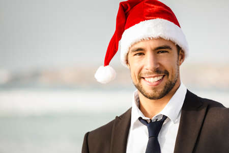 Good look young man in outdoor wearing a Santa hat and smilingの写真素材